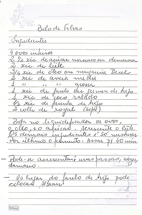 Página do caderno da Laura com a receita de Bolo de Fibras escrita à mão em caneta azul, em folha pautada